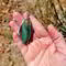 Gary Green Jasper pendant wrapped in sterling silver, held in hand to show size and design, featuring green and tan hues.